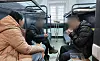 North Korean prisoners of war, identified by their surnames Baek and Ri, captured by Ukrainian forces, eat food sent by North Korean defector groups while meeting with a documentary producer at a prisoner camp in Ukraine on Oct. 28. A hand-drawn portrait of North Korean leader Kim Jong-un can be seen on the wall above their bed, in this photo provided by a North Korean defectors' activist group on Oct. 30. [YONHAP]
