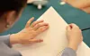 Close-up of hands reading a braille document on a table.