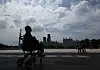 Silhouetted wheelchair user at the National Museum of Korea with Seoul skyline and pedestrians in the background.