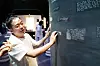 A visitor reads braille text mounted on a dark exhibition panel at Modu Theater in Seoul.