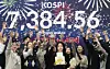 Employees celebrate in front of a screen showing the Kospi closing price at the dealing room of Woori Bank headquarters in Jung District, central Seoul, after the index broke through the unprecedented 7,000-point mark on May 6. [NEWS1]