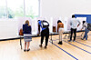 A group of people make their choices on their ballots in private voting booths set up on a long table. [GETTY IMAGES PRO]