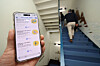 A Posco employee holds up a phone displaying the group’s internal app on a staircase at the Posco Center in Gangnam District, southern Seoul, on April 6. The screen lists various challenges that are designed to use less electricity and fuel. Posco Group said employees from its 19 domestic affiliates joined the “S.A.V.E. Challenge” campaign to support the government’s energy-saving policy. [YONHAP]