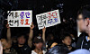 People hold signs claiming that there was election fraud in the June 3 local elections in front of Polling Station No. 2 in Jamsil 7-dong in southern Seoul on Thursday. [YONHAP]