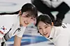 Korean women's curling team members Seol Ye-eun, left, and Kim Su-ji sweep during the delivery of the final stone in the fourth end of their round-robin match against Japan at the Cortina Curling Olympic Stadium during the 2026 Milan-Cortina Winter Olympics in Cortina d’Ampezzo, Italy, on Feb. 15. [YONHAP]