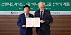 Hana Financial Group Chairman Ham Young-joo, left, and Standard Chartered Group CEO Bill Winters hold a signed agreement during an MOU ceremony on global business and digital asset cooperation at Hana Bank headquarters in Jung District, central Seoul, on March 13. [HANA FINANCIAL GROUP]