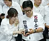 Independent candidate Han Dong-hoon, with his wife Jin Eun-jeong beside him, checks the confirmation of his win on his mobile phone on June 4 at his campaign office in Busan's Buk District. [YONHAP]