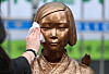 A staff member from the Korean Council for Justice and Remembrance cleans the Statue of Peace after the barricade surrounding it was removed for the first time in more than six years, on April 1, in front of the former Japanese Embassy in Jongno District, central Seoul. [NEWS1]