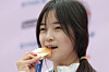 Korean snowboarder Choi Ga-on bites her gold medal during a press conference at the Korea House in Milan on Feb. 14 after winning the gold medal in the women's halfpipe snowboarding event at the 2026 Milan-Cortina Winter Olympics at Livigno Snow Park in Livigno, Italy. [NEWS1]