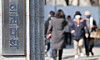 Pedestrians pass by near a medical school in Seoul on the March 13. [YONHAP]