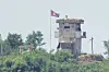 A soldier stands at a North Korean military guard post flying a national flag, seen from Paju, Gyeonggi, on June 26, 2024. [AP/YONHAP]