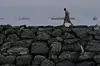 A man walks along the shore as oil tankers and cargo ships line up in the Strait of Hormuz, seen from Khor Fakkan, United Arab Emirates, on March 11. [AP/YONHAP]