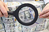 An employee at Hana Bank's counterfeit response center in central Seoul examines dollars bills on March 5. [YONHAP]