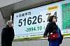 Pedestrians walk past an electronic quotation boards displaying the Nikkei Stock Average on the Tokyo Stock Exchange along a street in Tokyo on March 9, 2026. [AFP/YONHAP]