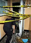 A police officer ducks under crime scene tape restricting access to the burnt out apartment in Ulsan in September 2006. [SCREEN CAPTURE]