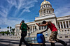 People carry containers of water past the Capitol in Havana, May 27. [AP/YONHAP]