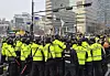 Members of Solidarity Against Disability Discrimination stage a boarding protest at a crosswalk near a bus stop in Gwanghwamun in Jongno District, Seoul, on March 27, as police manage the demonstration during morning commute hours. [YONHAP]