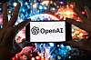 The OpenAI logo is seen displayed on a cell phone in front of an image on a computer screen generated by ChatGPT's Dall-E text-to-image model in Boston on Dec. 8, 2023. [AP/YONHAP]