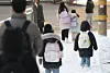 Children and their caretakers walk down a slope near an elementary school in Seodaemun District, western Seoul, on Feb. 2. [YONHAP]