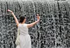 A person takes a photo against the backdrop of an artificial waterfall at Cheonggyecheon in Seoul on June 1, as hot weather continues. [YONHAP]