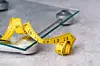 A yellow tape measure lies on top of a glass weighing scale. [GETTY IMAGES BANK]