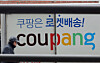 A pedestrian walks by a Coupang logistics center in Seoul on Feb. 10. [NEWS1]