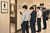 An AI-generated image of investors checking stock trades while waiting in line for the restroom [CHATGPT]