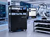 Robotic arm operating in a futuristic factory with digital displays and automated equipment.