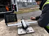 Worker operating a drone setup with a laptop beside a vehicle outdoors.