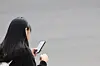 A student uses her phone on her way home from school in central Seoul on Nov. 4, 2024. [YONHAP]