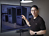 Man pointing at a screen displaying server racks in a data center.