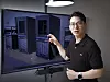 Man pointing at a screen displaying server racks in a data center.