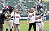 Jensen Huang and Park Jeong-won stand on the field and exchange greetings near Doosan Bears mascots at a baseball stadium.