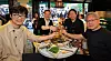 Four business leaders sit around a table with grilled meat, vegetables and drinks at a Korean barbecue restaurant in Seoul.
