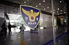 Interior lobby with a large police shield emblem on glass and people standing in the background.