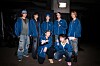 BTS members in blue outfits pose together backstage before a concert.