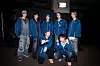 BTS members in blue outfits pose together backstage before a concert.