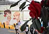 Tourists posing near a large BTS mural in a colorful Busan alley.