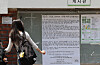Student stands by a campus bulletin board with a large protest notice about ballot paper shortages.
