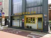 Storefront with Korean signage, large windows, and potted plants on a city street.