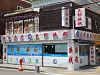 Corner building with red Chinese signs, glass windows, and a white storefront along a street.