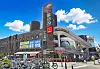 Urban market building with Korean signs, bicycles in front, and people walking along the sidewalk.