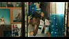People in a room with wall posters, a window, and a blue translucent panel.