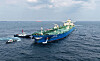 HMM crude oil tanker approaches an offshore unloading buoy near Ulsan with escort boats nearby.