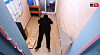 A narrow detention cell with a floor mat, small shelf, toilet and posted notices.
