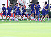 South Korea soccer players in blue training kits run and stretch on a practice field.
