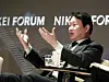 SK Group Chairman Chey Tae-won speaking at a Nikkei Forum panel in Tokyo with a microphone and water glass on the table.