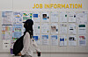 A person walks in front of a job-post board in a college in Seoul on June 11.