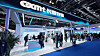 People stand and walk around a CXMT exhibition booth in a large convention hall.