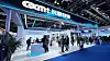 People stand and walk around a CXMT exhibition booth in a large convention hall.